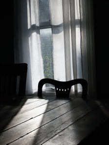 An artful photograph of a chair and a window.